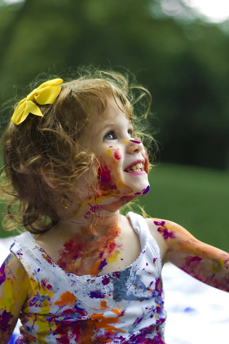Smiling young child playing with colourful paint