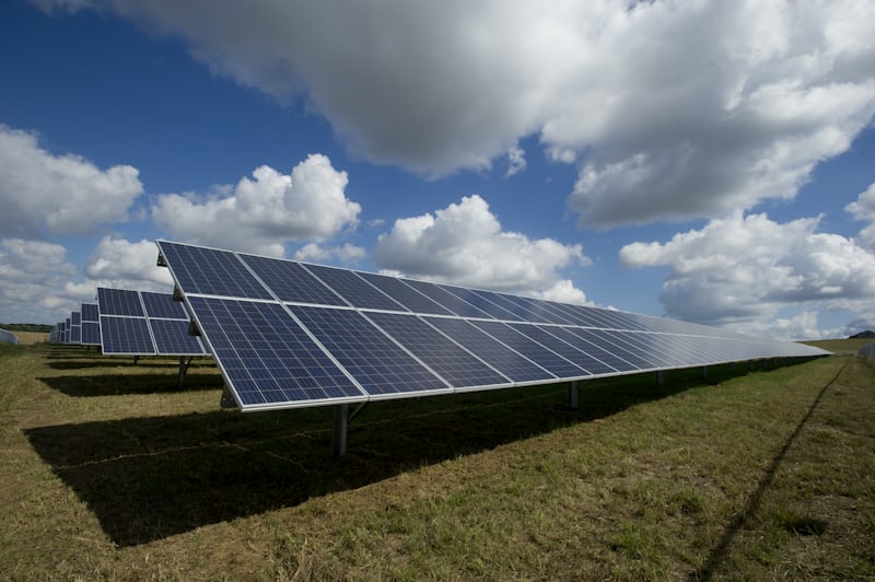 Rows of solar panels in a field under a blue sky